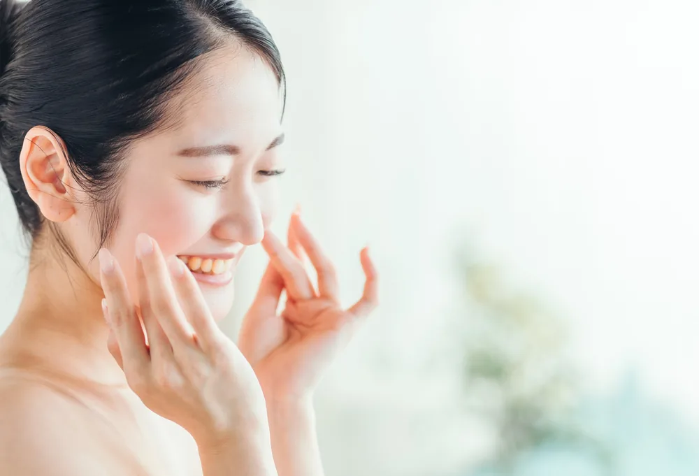 洗い上がりの素肌に触れて微笑む女性